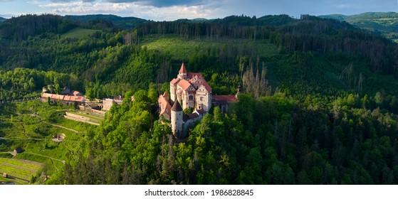 Panoramic, Aerial View Of Ancient Royal Moravian Castle Pernstejn With New Vrchnostenska Garden, Illuminated By Sun Against Dark Forest. Aerial Photography. Bohemian-Moravian Highlands, Czech Castles