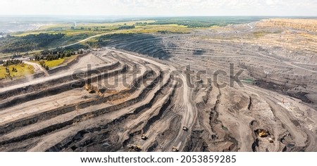 Panoramic aerial view of coal mine. Open pit mine industry, big yellow mining truck for coal quarry. Open coal mining anthracite mining. Pit on coal mining by open way. Rock loading in trucks