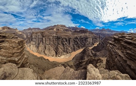 Panoramic aerial view of Colorado River weaving through valleys and rugged terrain seen from Plateau Point, Bright Angel Trail, South Rim, Grand Canyon National Park, Arizona, USA. Brown dirty water