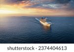 Panoramic aerial view of a cruise ship traveling over the ocean during golden summer sunset time with copy space