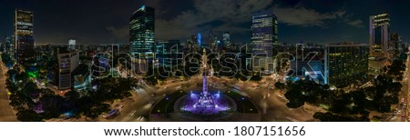 Panoramic aerial view of the famous Reforma avenue full of trees and huge office buildings illuminated by the night lights of the city