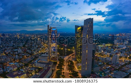 Panoramic aerial view of the famous Reforma avenue full of trees and huge office buildings illuminated by the night lights of the city