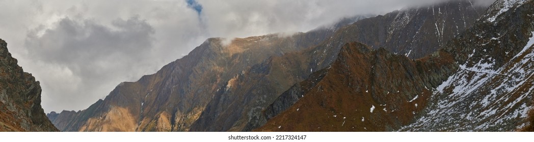 Panoramic Aerial View Of A Mountain Ridge. Stormy Skies And Steep Mountain Top Sprinkled With Snow