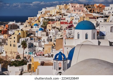 Panoramic Aerial View of Oia Village and Blue Dome Church in Santorini Island, Greece - Traditional White Houses in the Caldera Cliffs - Sunset