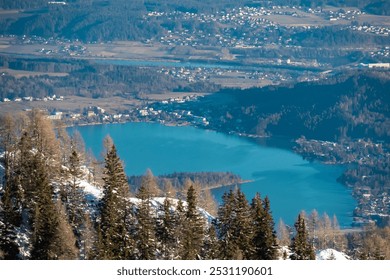 Panoramic aerial view of picturesque alpine lake Faak seen from Karawanks, Carinthia, Austria Slovenia border. Vibrant blue waters contrasting with surrounding green forests and snow-capped mountains - Powered by Shutterstock