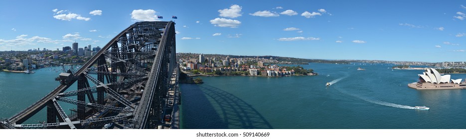 Panoramic Aerial View Of Sydney Harbour With Sydney Harbour Bridge And The Opera House From The South-eastern Pylon Containing The Tourist Lookout Towards North Sydney, New South Wales Australia.