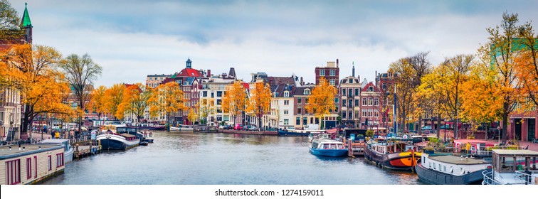 Panoramic autumn view of Amsterdam city. Famous Dutch channels and great cityscape. Gloomy morning scene of Netherlands, Europe. Traveling concept background.