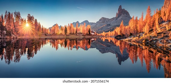 Panoramic autumn view of popular tourist destination - Federa lake among red larch trees. Spectacular sunrise in Dolomite Alps. Colorful morning scene of Italy. Beauty of nature concept background.
				