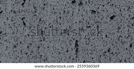 Panoramic background of dark gray volcanic stone wall texture with a porous surface