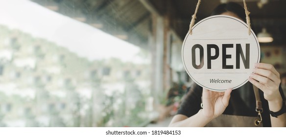 Panoramic banner. friendly waitress woman turning Open sign board reopen after coronavirus quarantine is over in cafe coffee shop ready to service, restaurant, take away, food and drink concept