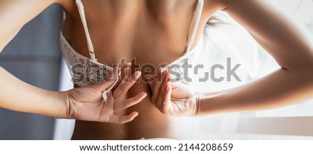 Panoramic banner image of back view of beautiful sexy woman unhooking and taking off or putting on her white lace underwear bra rear view in boudoir room. Wide crop, web page,template with copy space.