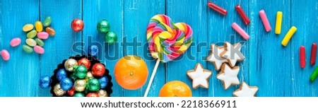 Panoramic banner for Saint Nicholas Day or Nikolaus Tag in German language. Traditional holiday in Germany, Europe. Decorative border - sweets, candy, cookies, satsuma and rainbow lolly pop. Top view