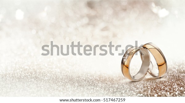 Panoramic banner of two\
upright gold wedding bands symbolic of love and romance on a\
textured glitter background with copy space for your greeting or\
congratulations