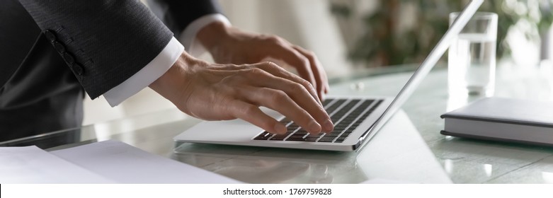 Panoramic banner wide view of successful male CEO typing on modern laptop keyboard, browse internet in office, confident businessman text message check mail on computer gadget, technology concept
