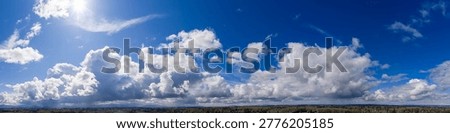 Panoramic blue sky filled with dramatic white clouds over a mountain horizon — Cloudscape in British Columbia, Canada.
