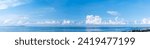 Panoramic blue sky with white fluffy clouds and sea