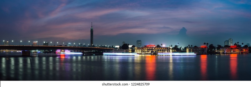 Panoramic of Cairo city center at night, long exposure with light trails of moving boats on the Nile river.