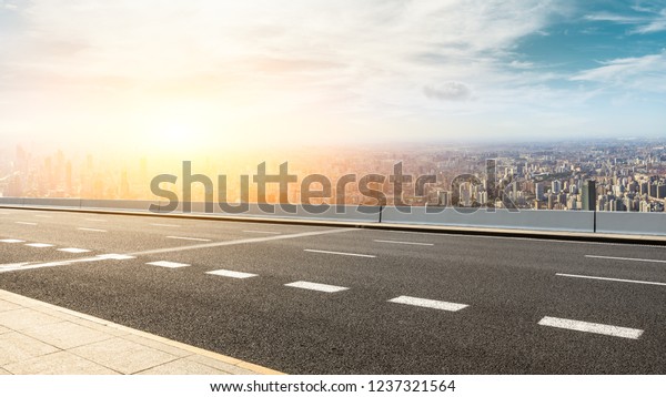Panoramic city skyline and buildings with empty\
asphalt road at\
sunset