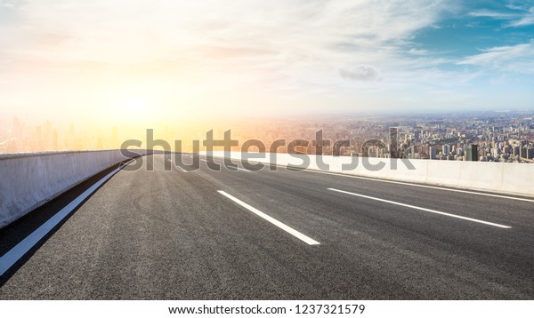 Panoramic city skyline and buildings with empty
asphalt road at
sunset