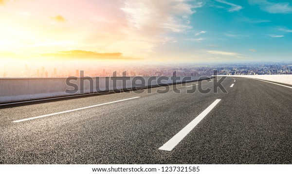 Panoramic city skyline and buildings with empty\
asphalt road at\
sunset