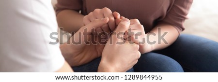 Panoramic close up image couple sitting on couch man holding hands beloved woman, gesture empathy support, symbol sincere feelings declaration of love horizontal photo banner for website header design