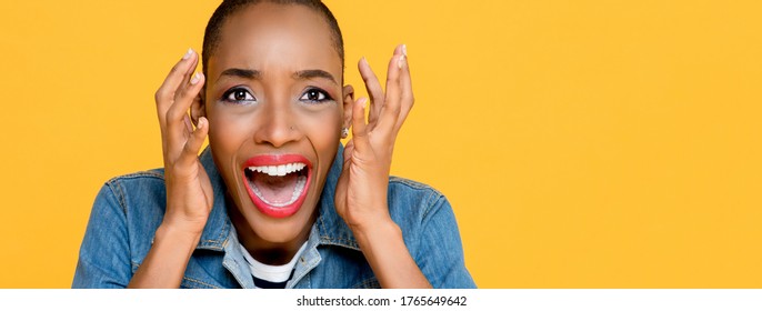 Panoramic close up portrait of scared young African American woman screaming with both hands raised isolated on studio yellow background