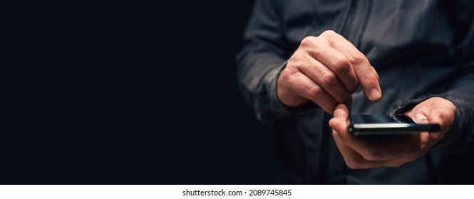 Panoramic closeup of male hands using smartphone for text message communication, copy space included in this low key image with selective focus