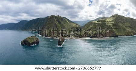 Panoramic drone view of Ilheus da Ribeira da Janela on Madeira island, showing volcanic sea stacks, terraced green cliffs and Atlantic waves
