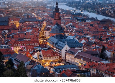 Panoramic, elevated view of the festive decorated old town of Heidelberg, Germany, around the Heiliggeistkirche during winter dusk