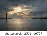 Panoramic Exposure done from a Cruise ship, while arriving at Lisbon at sunrise, of the 25th April Bridge and Tagus River, with Lisbon on the left bank and the Sanctuary of Christ the King, Portugal