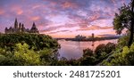 A panoramic of the gothic architecture of the Canadian Parliament Building overlooking the Ottawa River in Ottawa, Ontario, flanked by lush green nature during a magenta sunset.