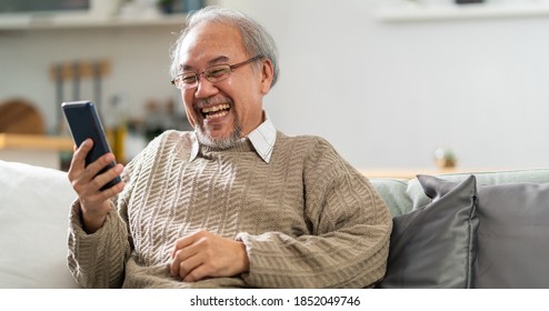 Panoramic Happy retirement elderly man sitting on sofa at living room use cellphone to make video call to his family with laugh and smile. Communication Technology with senior people at home. - Powered by Shutterstock