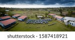 A panoramic high angle shot of a camp with people in identical uniforms standing in the yard