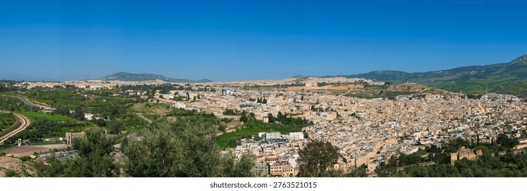Panoramic high angle view of the ancient medina of Fez in Morocco with its dense traditional buildings and historic architecture under a clear sky with hills in the background, labyrinthine streets
