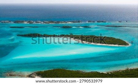 Panoramic high angle view of tropical green cays surrounded by vibrant turquoise ocean water in the Bahamas.