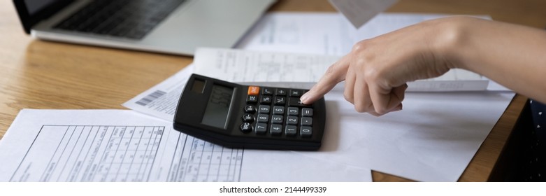 Panoramic horizontal cropped image unrecognizable female hand using calculator, table with heap of bills close up photo. Personal budget control, family finances management, pay bills, savings concept