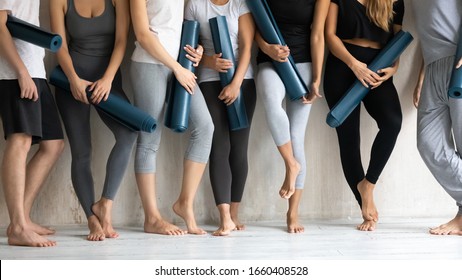 Panoramic image cropped view group of girls and guys standing barefoot of warm floor in sport studio wait for class starts, people holding mats pose near wall. Concept of wellness, healthy lifestyle