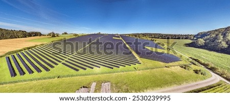 Panoramic image of a large solar field on a green meadow in daylight in summer
