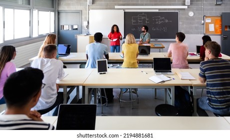 Panoramic Image Of Multiracial Students Listening To African American Female Classmate Giving Oral Presentation.