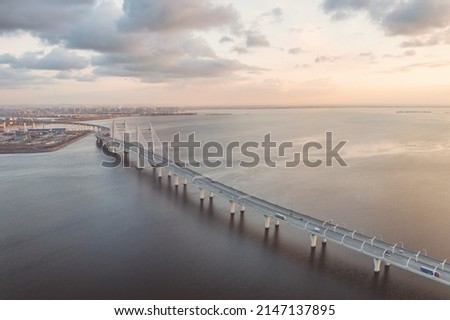 Panoramic industrial landscape with  elevated highway over sea in Saint Petersburg, Russia aerial view at sunset. Landscape with bridge, cloudy sky and calm sea
