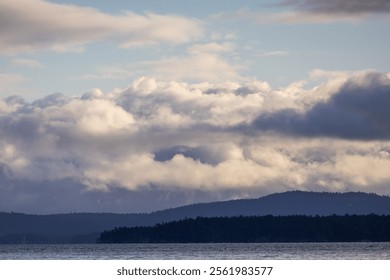 Panoramic landscape featuring a cloudy sky over forested hills with calm waters below, creating a serene and tranquil atmosphere.