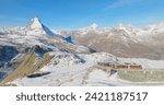 Panoramic landscape of Gornergrat bahn railway climibing up the summit station with Matterhorn mountain peak background in Zermatt on a sunny winter day. Swiss Alps, Switzerland travel journey trip.