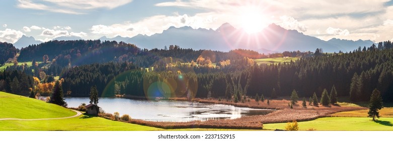 panoramic landscape with lake aund mountainrange against sky with sun