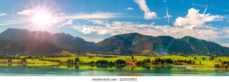 panoramic landscape with lake aund mountainrange against sky with sun