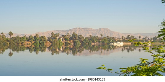 Panoramic Landscape View Across Nile River To Luxor West Bank With Mountains And Reflection In Water