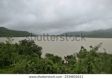 Panoramic landscape view of beautiful scenic Mulshi lake on a cloudy monsoon day. Surrounded by lush green mountains and dense fog, it is a famous tourist spot in Mulshi, Pune, Maharashtra, India