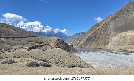 Panoramic landscape view of Jomsom (elevation 2,700m), the administrative 
headquarters of Mustang District, located along the banks of Kali Gandaki River — 
the world's deepest river gorge — in Gandaki Province, western Nepal. 
Flanked by Mt. Dhaulagiri (8,167m) to the west and Mt. Nilgiri to the south, 
the semi-arid high-altitude desert terrain contrasts dramatically with 
the turquoise river below. Jomsom serves as the gateway to Upper Mustang 
and the sacred Muktinath Temple (3,800m). Unique Thakali and Tibetan-influenced 
culture, prayer flags, whitewashed stone houses, and dramatic Himalayan backdrop 
