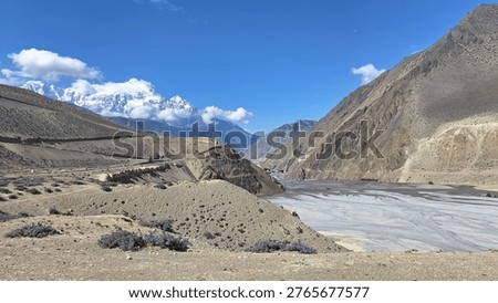 Panoramic landscape view of Jomsom (elevation 2,700m), the administrative 
headquarters of Mustang District, located along the banks of Kali Gandaki River — 
the world's deepest river gorge — in Gandaki Province, western Nepal. 
Flanked by Mt. Dhaulagiri (8,167m) to the west and Mt. Nilgiri to the south, 
the semi-arid high-altitude desert terrain contrasts dramatically with 
the turquoise river below. Jomsom serves as the gateway to Upper Mustang 
and the sacred Muktinath Temple (3,800m). Unique Thakali and Tibetan-influenced 
culture, prayer flags, whitewashed stone houses, and dramatic Himalayan backdrop 
