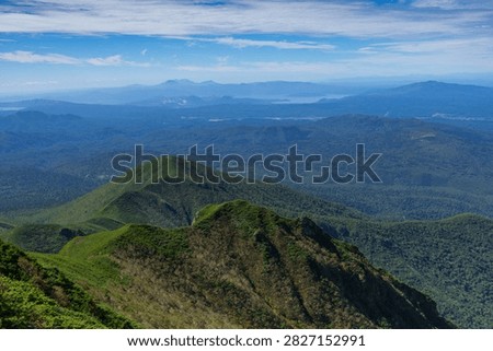 Panoramic mountain view while hiking Mount Shari in eastern Hokkaido, Japan. A panoramic view of green mountains and vast forests seen while hiking Mount Shari in eastern Hokkaido, Japan. This expansive landscape represents mountain trekking, outdoor adventure, nature, and scenic tourism in northern Japan.