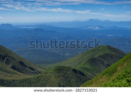 Panoramic mountain view while hiking Mount Shari in eastern Hokkaido, Japan. A panoramic view of green mountains and vast forests seen while hiking Mount Shari in eastern Hokkaido, Japan. This expansive landscape represents mountain trekking, outdoor adventure, nature, and scenic tourism in northern Japan.